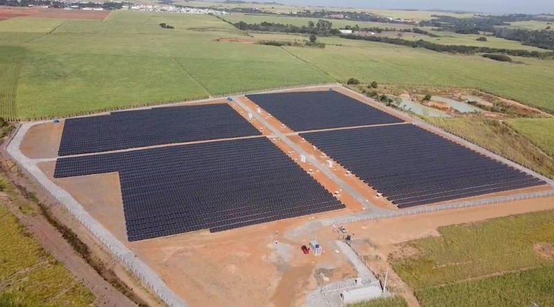 Foto registrada de cima de um terreno onde estão diversas placas de energia solar